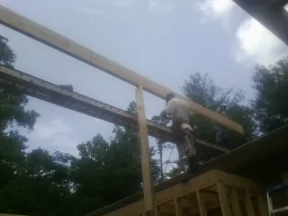 Carpenter setting a ridge beam over a new addition frame — Ice Dam Removal by Roofing Brothers in Columbiana