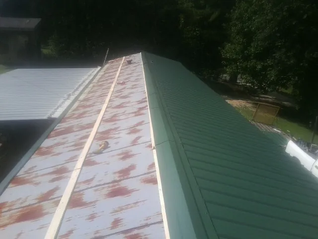 Old rusted panels beside newly installed green metal roofing — Wind Damage Roof Repair by Roofing Brothers in Columbiana