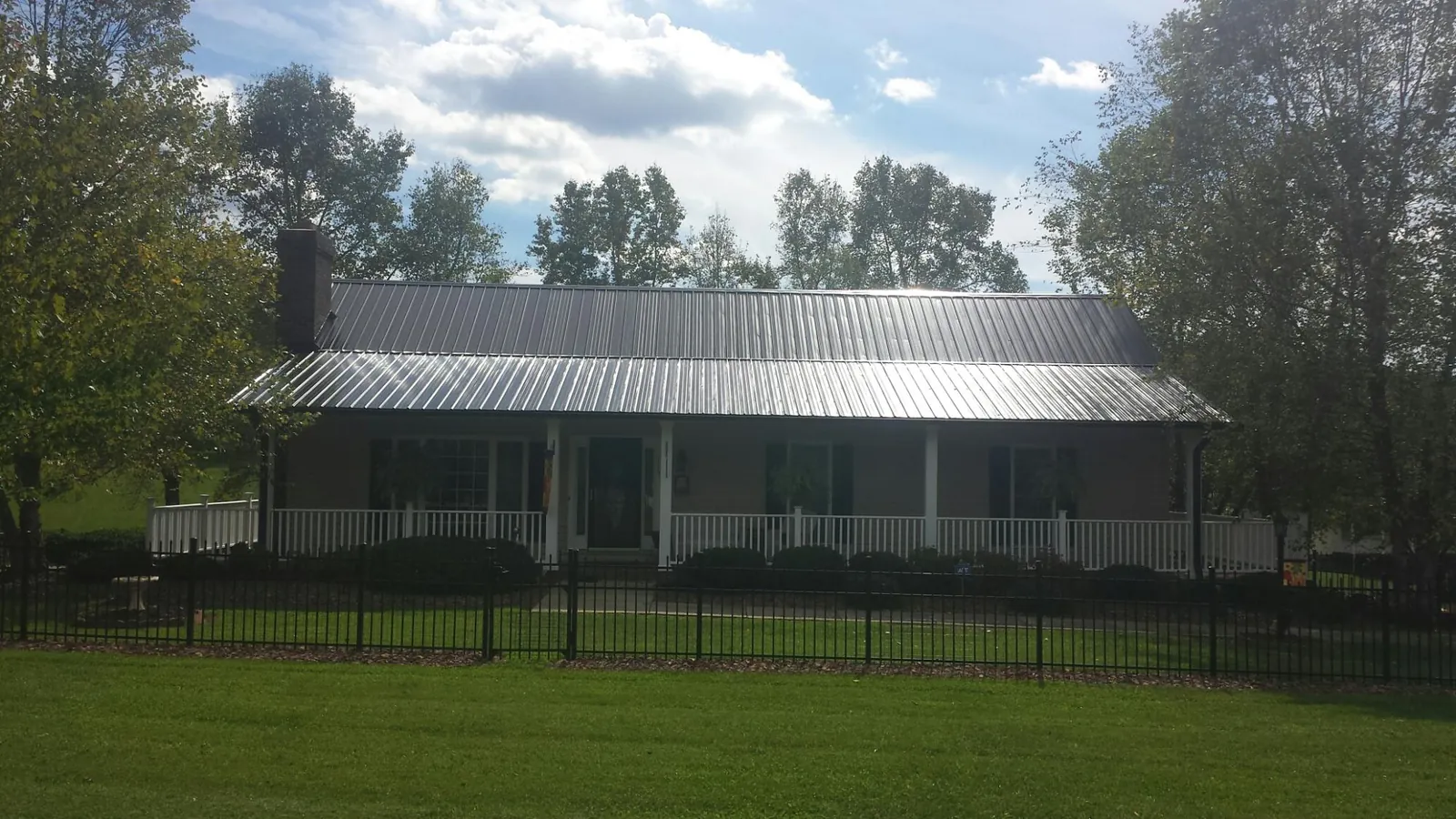 Gray metal roof on a brick ranch with a full width front porch — Gutter Guard Installation work by our crew in Columbiana