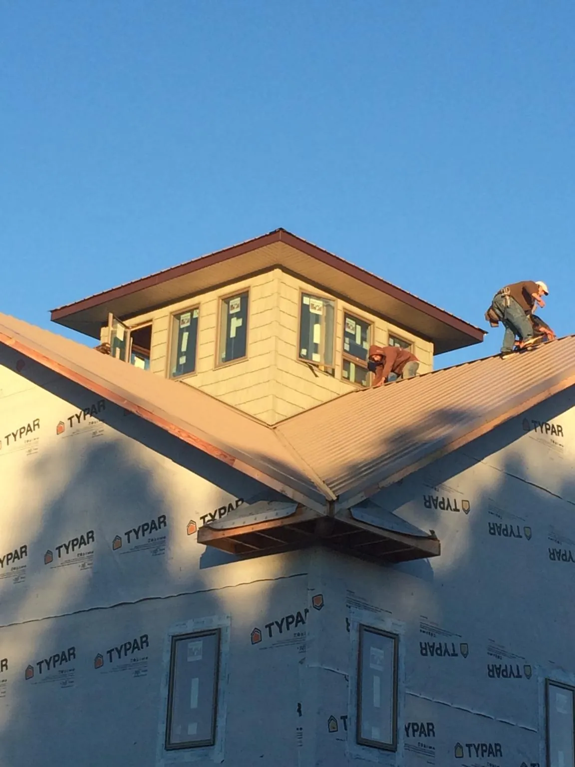 Roofers working around a rooftop cupola on a new metal roof at sunset — Roof Waterproofing in Columbiana by Roofing Brothers